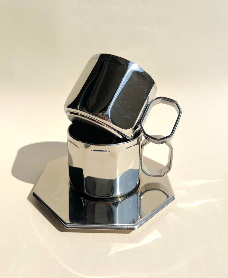 May include: Two silver metal cups with octagonal handles and a matching octagonal saucer.