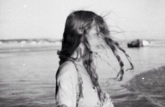This may contain: a woman standing in the water with long hair