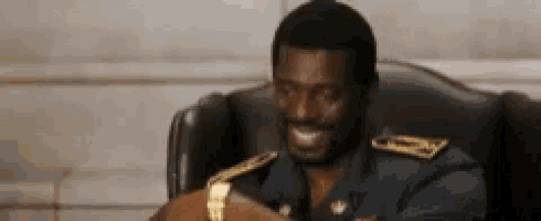 a man in a military uniform is sitting in a chair and smiling at the camera . a man in a military uniform is sitting in a chair and smiling at the camera .