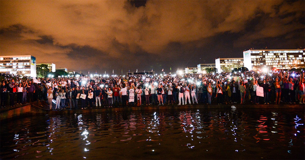 A imagem contém um grupo grande de protestantes reunidos.