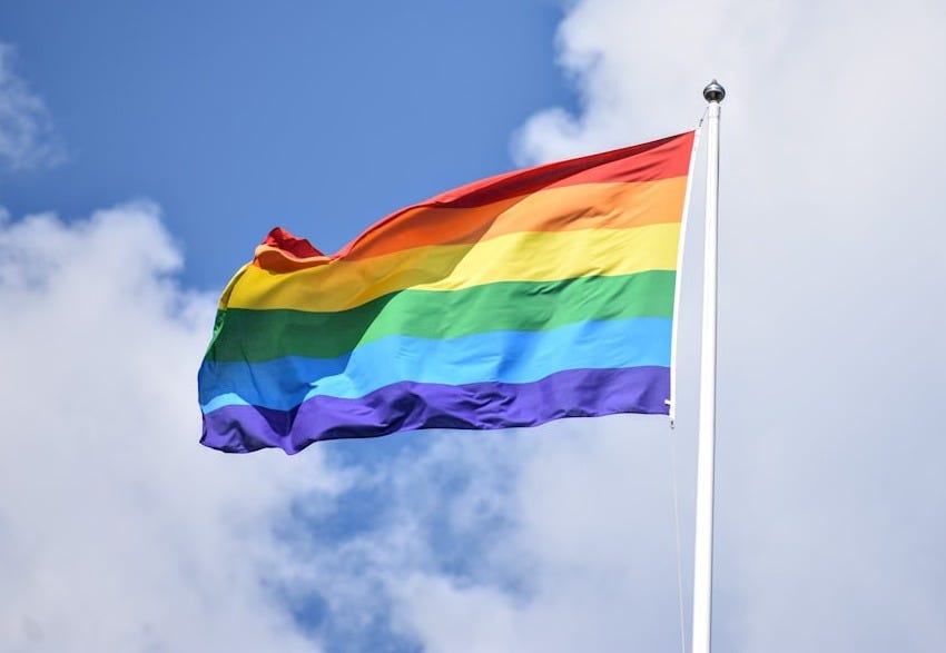 a rainbow flag flying high in the sky