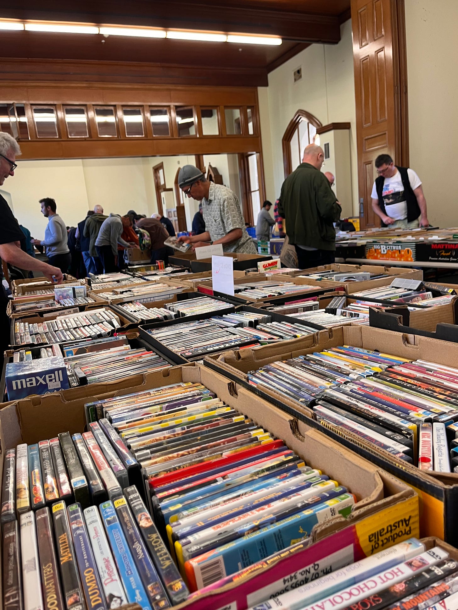 A room full of men looking through boxes of CDs and DVDs