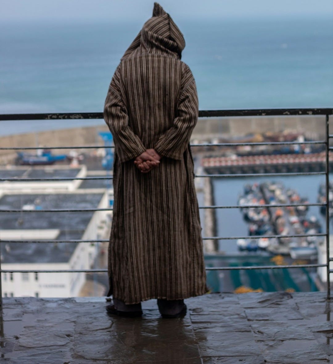 a person in a long coat standing on a balcony a person in a long coat standing on a balcony