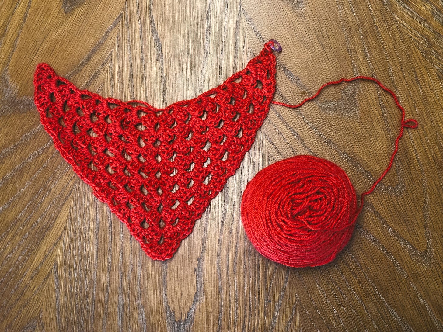 an almost finished red granny square bandana, still attached to a red ball of yarn an almost finished red granny square bandana, still attached to a red ball of yarn
