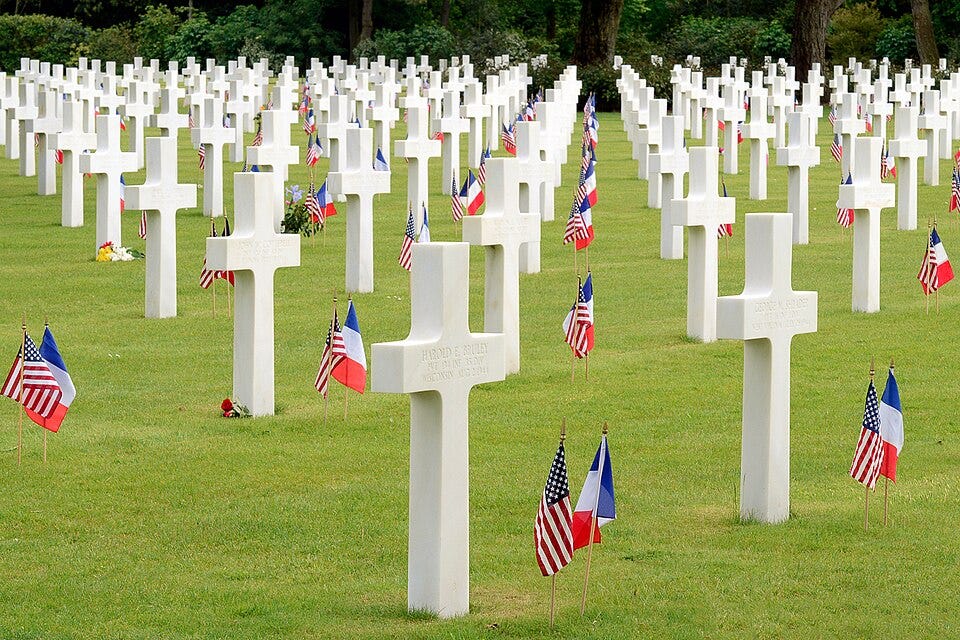 A field of white crosses with flags

AI-generated content may be incorrect.
