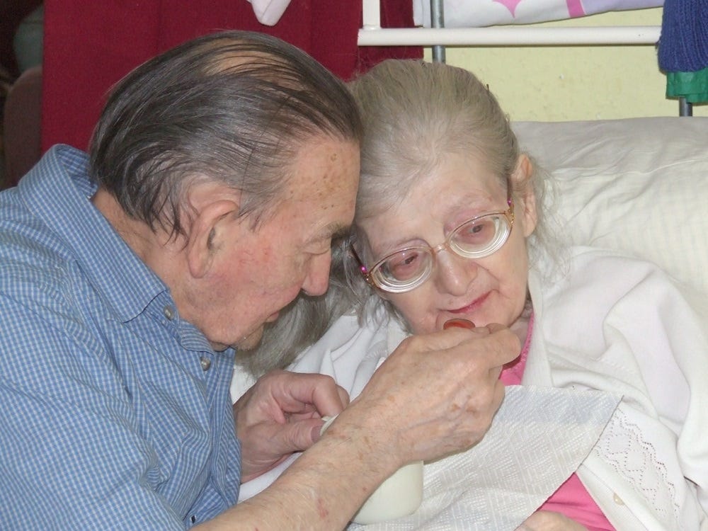 Peter helps Edith to take her meal. May 2007. 