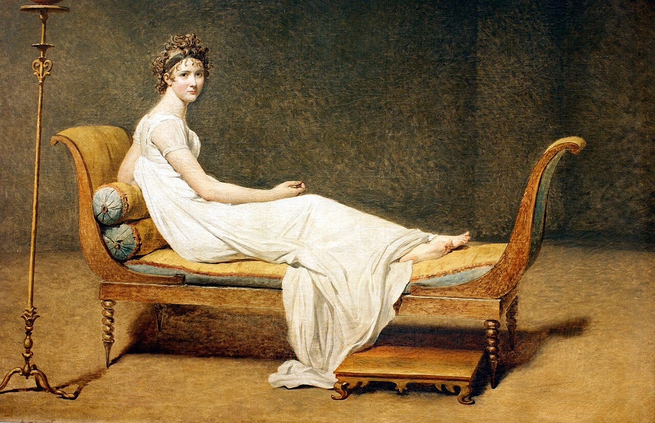 Young woman barefoot on a sofa against a bare background Young woman barefoot on a sofa against a bare background