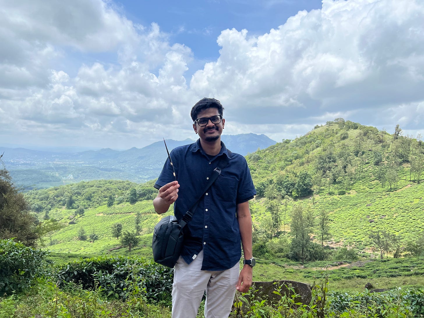 A man is standing with a mountain range in the background. 