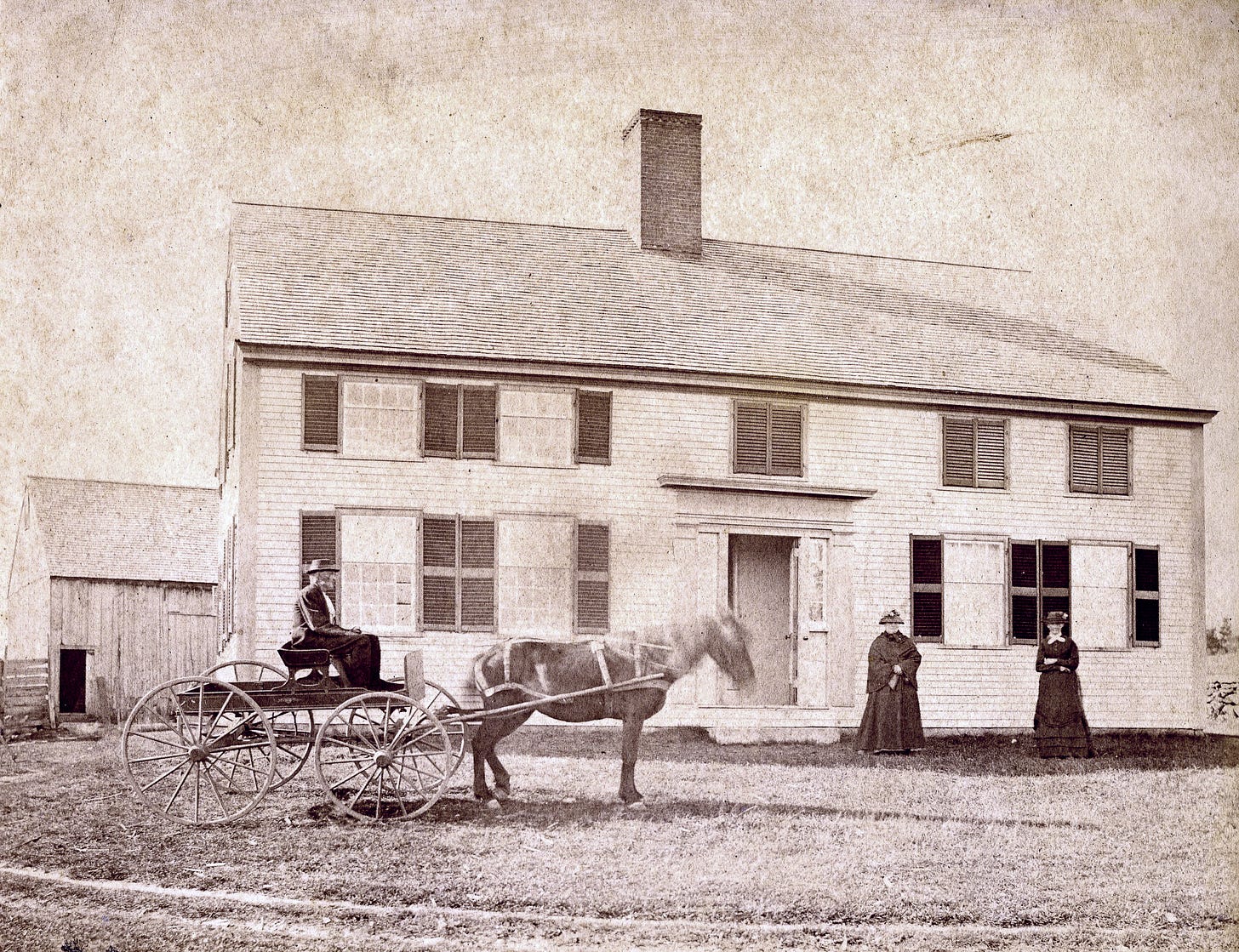 Man on horse drawn cart and two women in front of house