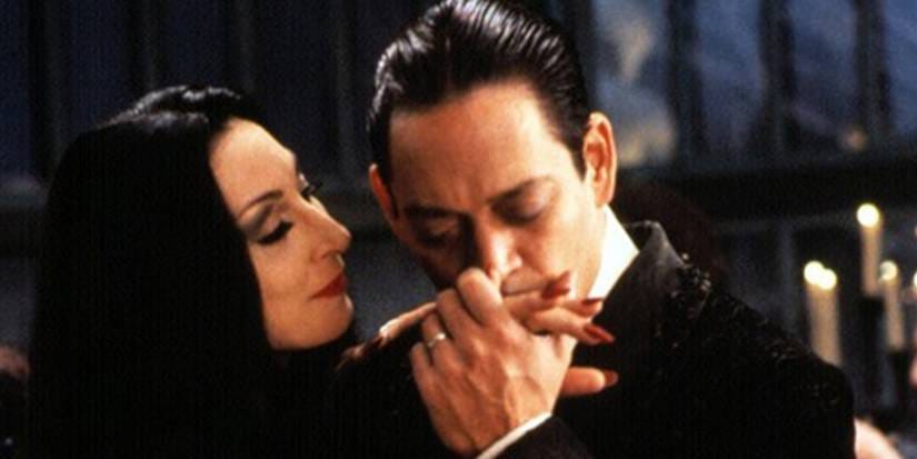 Gomez (Raul Julia) kissing the hand of his elegant and beautiful wife Moriticia (Anjelica Houston) in the 1990's film adaptation of The Addams Family