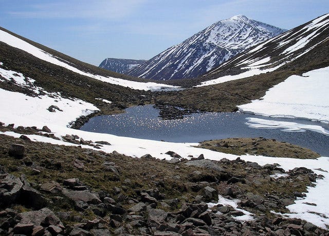 pool, snowfields, mountains rising above
