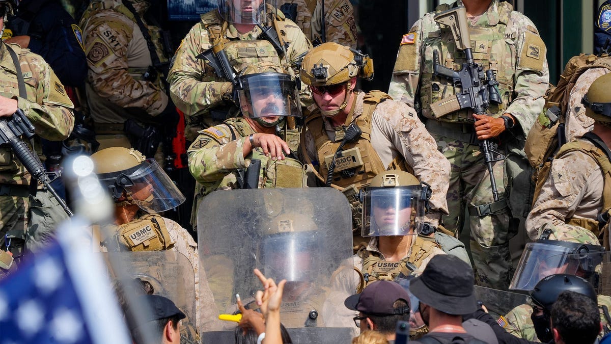 Marines and National Guard troops communicate as they deal with protesters on the front steps of the Edward Roybal Federal Building in Los Angeles, Calif., June 14, 2025.