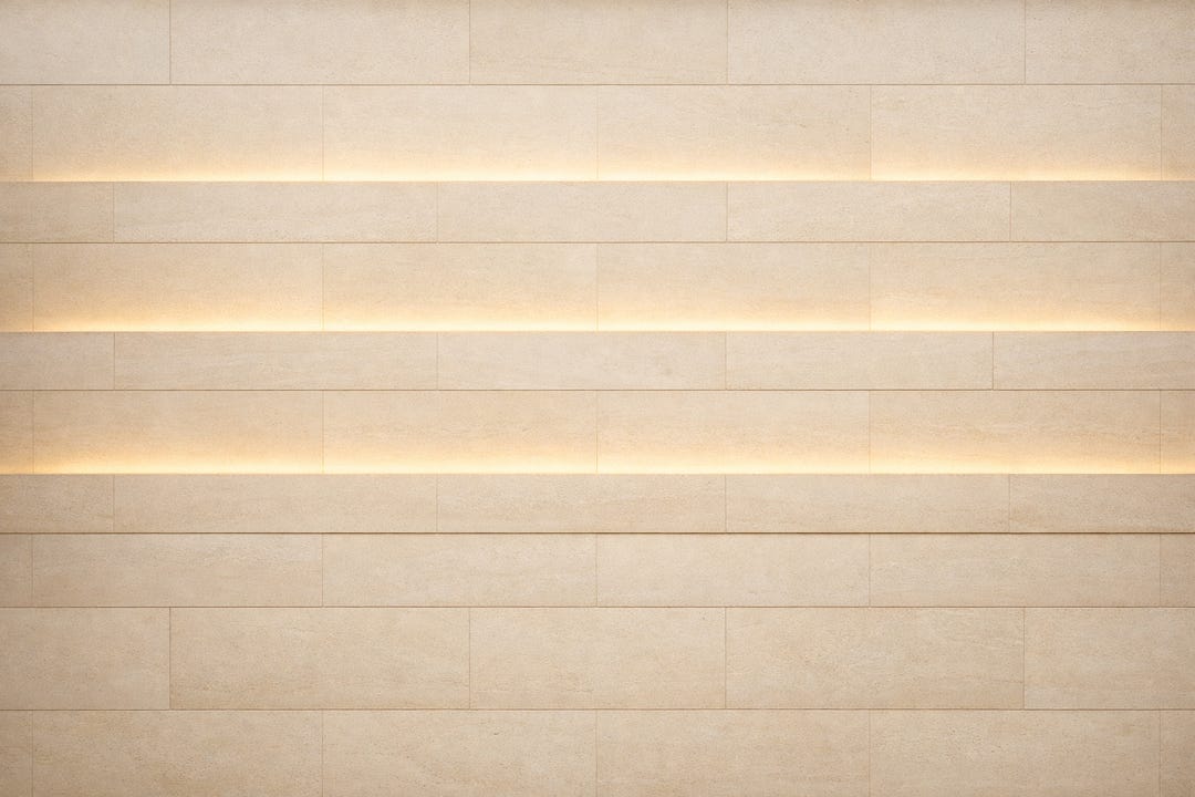 Soft horizontal bands of warm golden light across textured ivory stone, forming a quiet architectural rhythm.