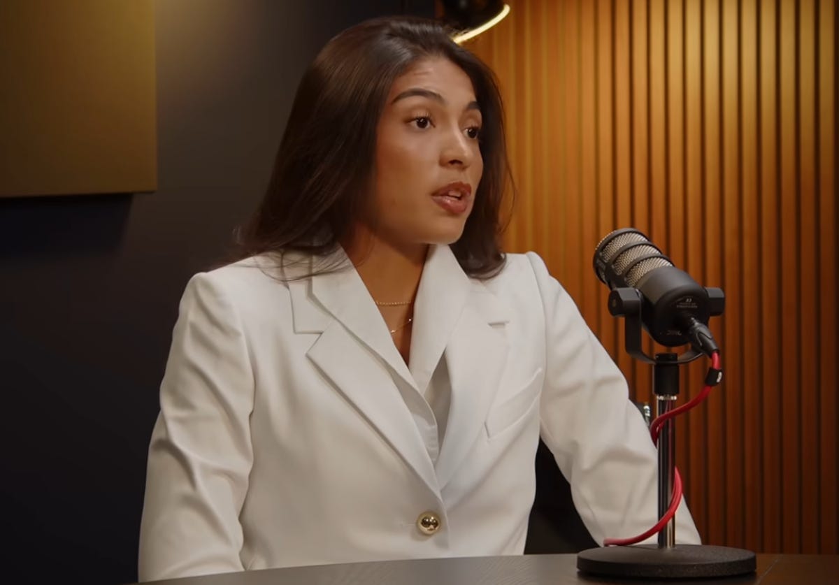 Woman dressed in white suit speaks into a microphone Woman dressed in white suit speaks into a microphone