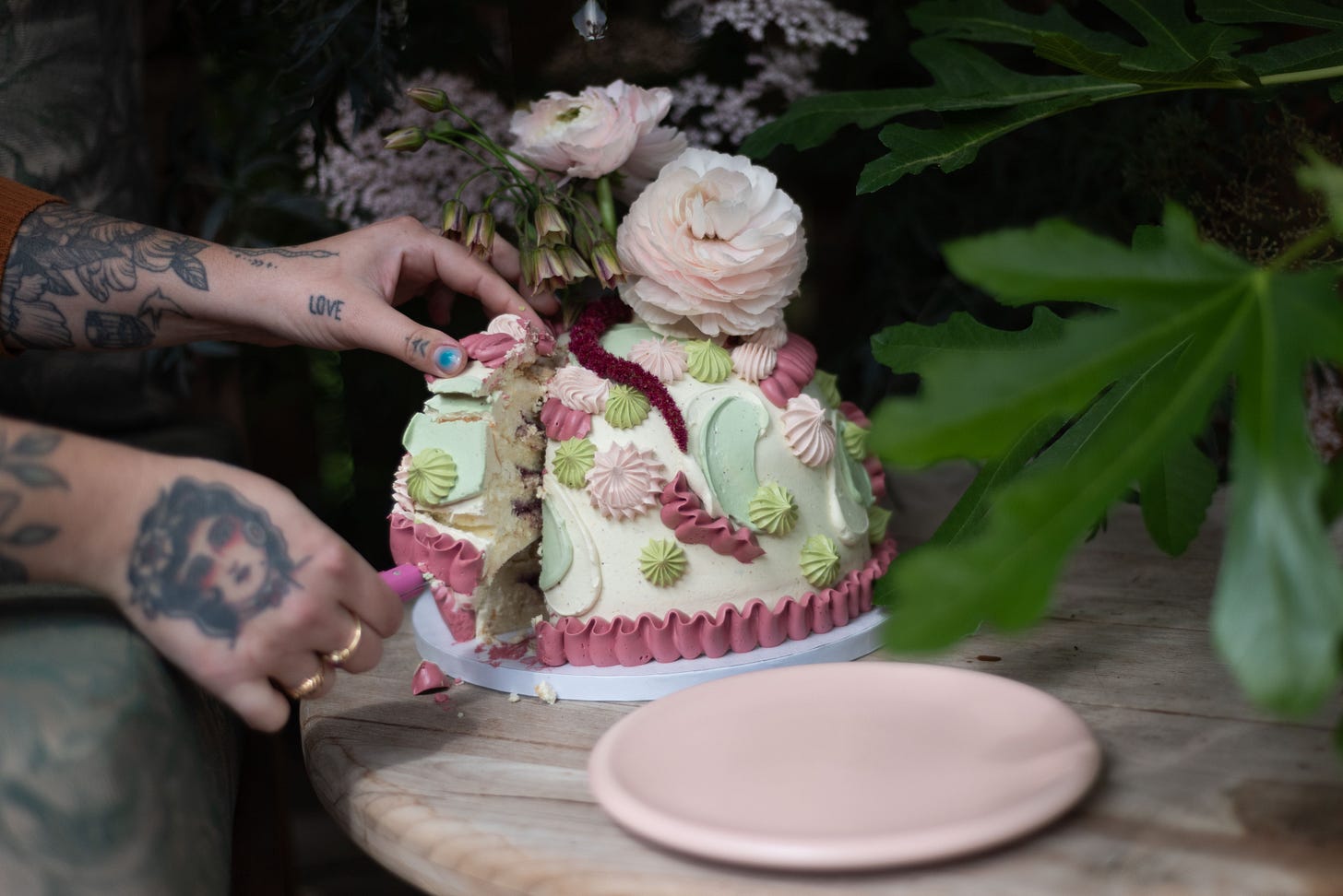 tattooed female hands reaches for and removes a piece of cake with a knife