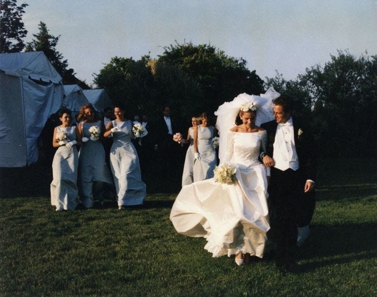 This may contain: a bride and groom walking in front of their wedding party on the grass with tents behind them
