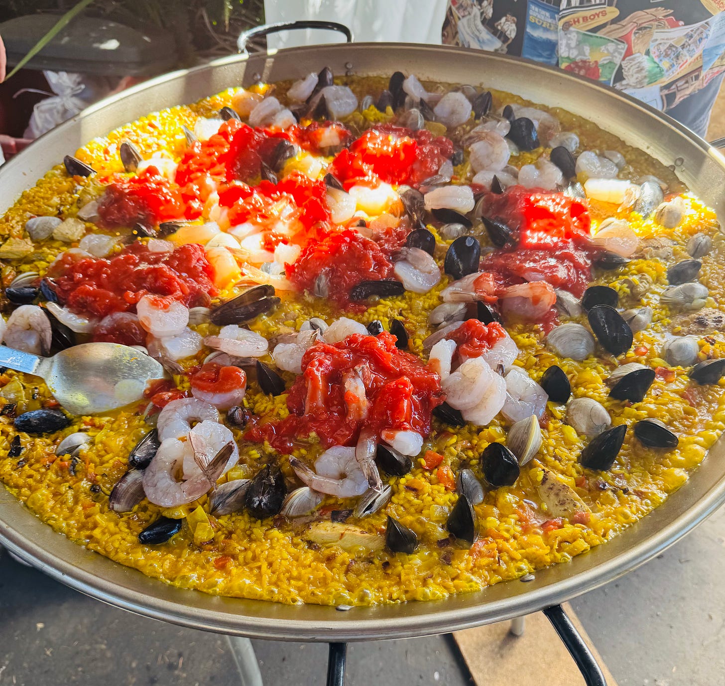 Shell fish and tomatoes are added to cooking paella