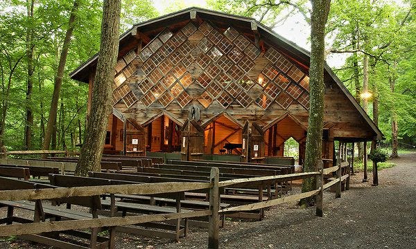 This may contain: an old church in the woods with wooden pews on the ground and benches around it This may contain: an old church in the woods with wooden pews on the ground and benches around it