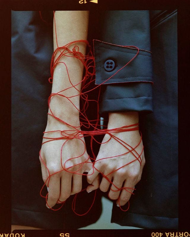This may contain: a woman's hands with red string attached to them