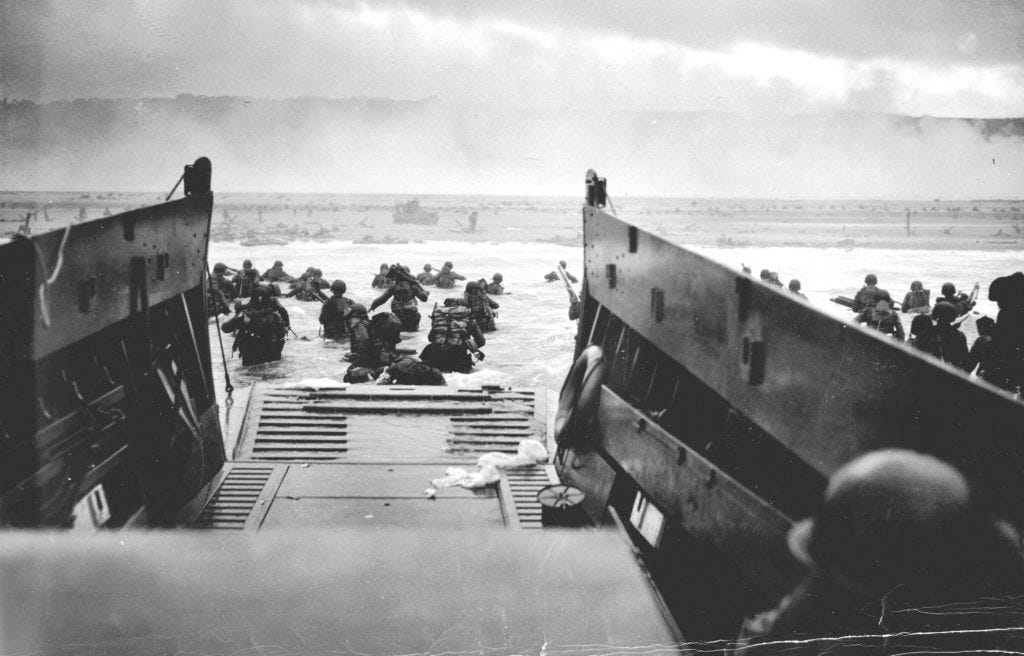 U.S. troops wade ashore from a Coast Guard landing craft at Omaha Beach during the Normandy D-Day landings near Vierville ...