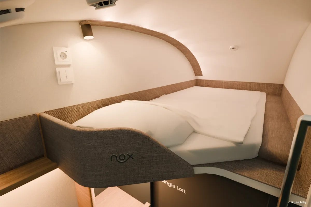Une image d’une cabine de train de nuit innovante et bien éclairée, avec un lit simple en hauteur.