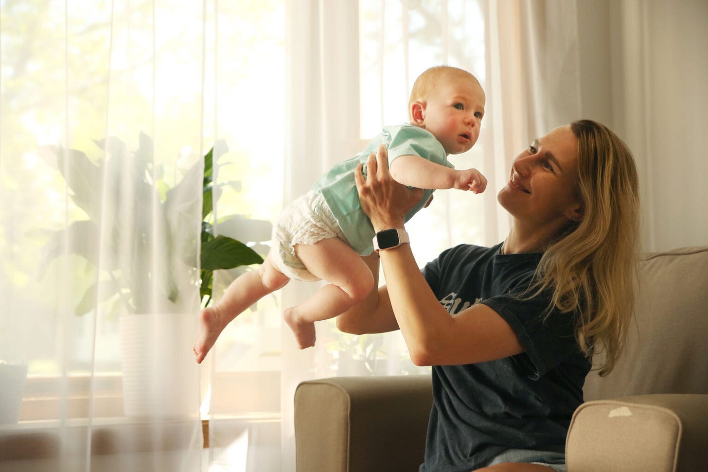 Ilona Biliaze plays with her 7-month-old son Brian in their Watertown home on May 12, 2025. (Makenzie Huber/South Dakota Searchlight)