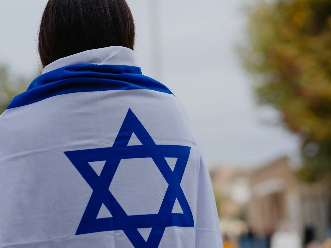 woman in white and blue hoodie standing near green trees during daytime