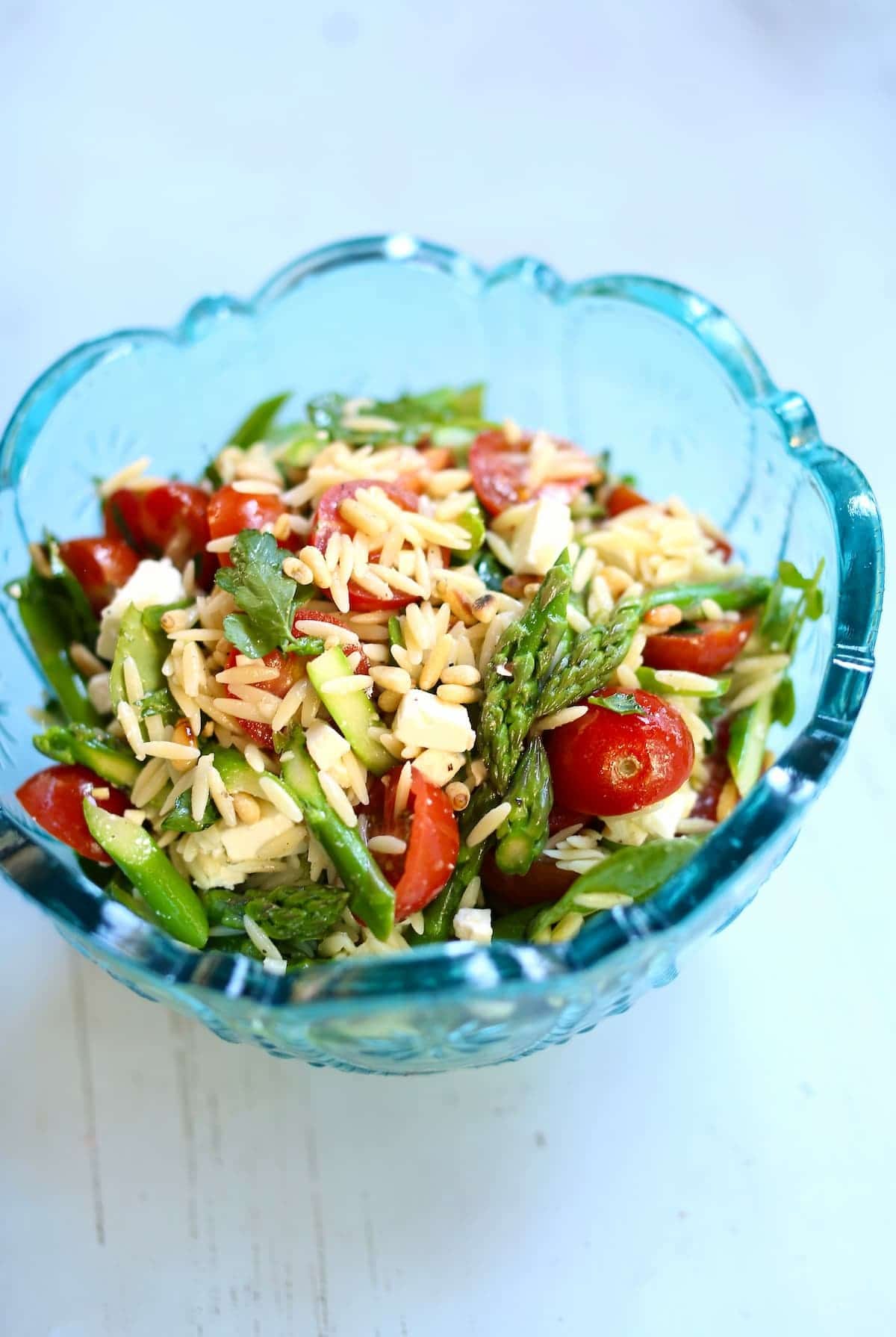 a blue bowl with a salad in it on a blue table.