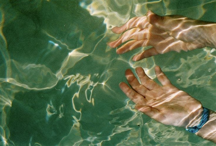 This may contain: two hands reaching for something in the water