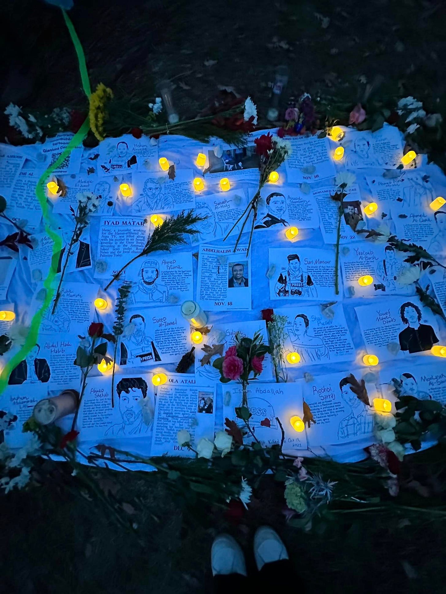Posters of killed journalists in Gaza, illustrated by Gianluca Costantini. Flowers and candles adorn the posters.