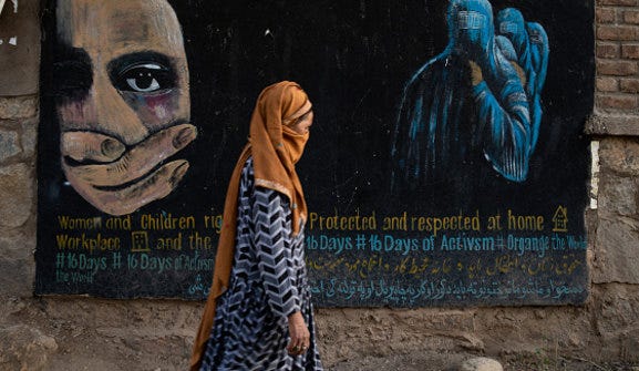 A woman walks past a mural calling for women and children’s rights in Afghanistan.