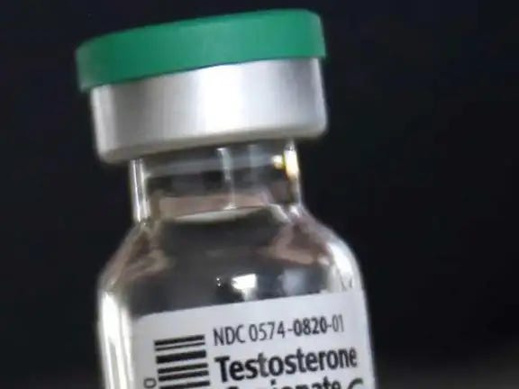 Glass vial of testosterone cypionate with a green cap, labeled NDC 0574-0820-01, photographed against a black background.