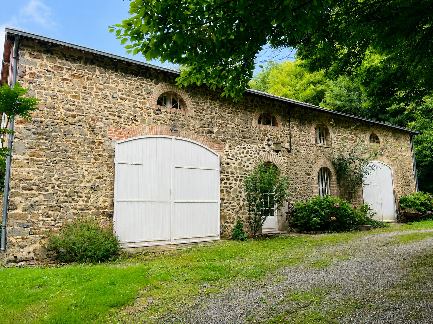 Exterior of a stone coach house in rural France showing thick old stone walls and facade.