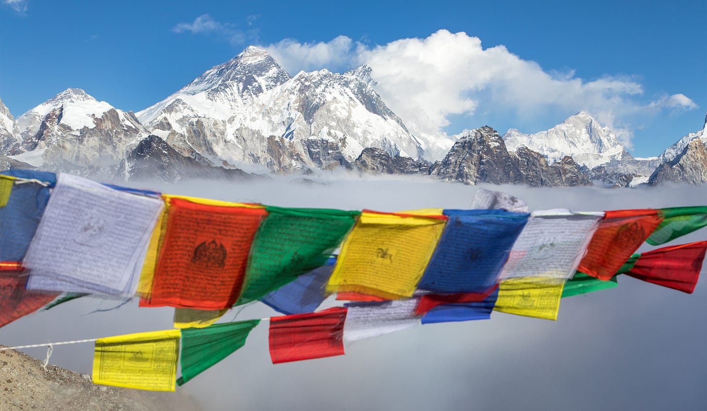 Tibetan prayer flags with a lake and snowy mountains in the background