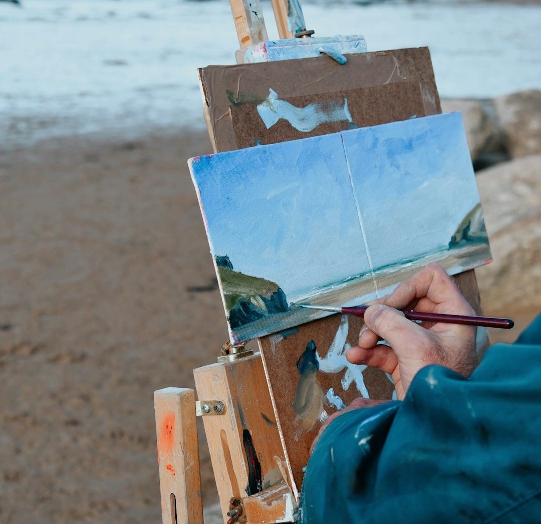 a person is painting on an easel on the beach