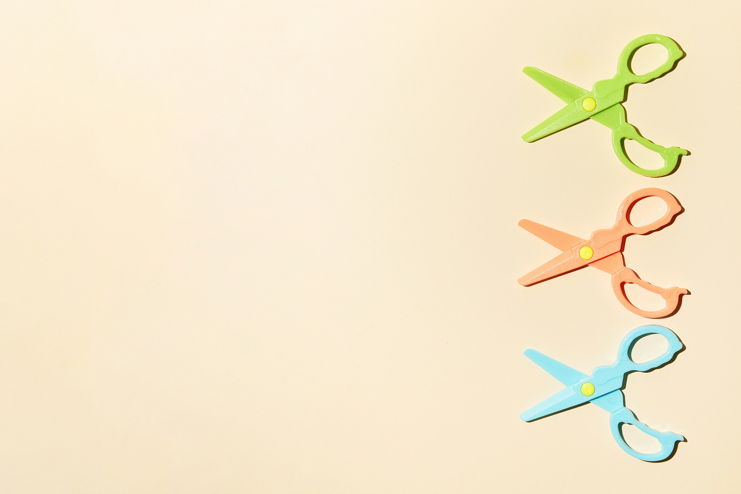 Three pairs of colored scissors on a beige background. 