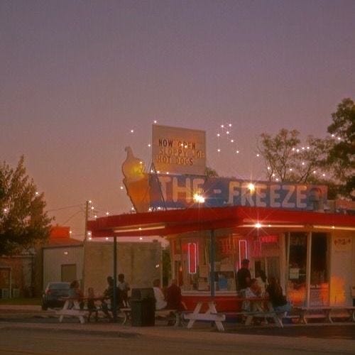 This may contain: people are sitting at tables outside the freezer