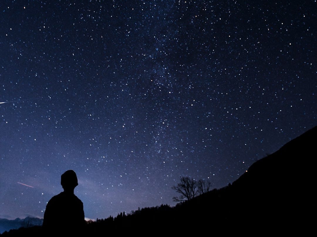 silhouette of man looking at milky way