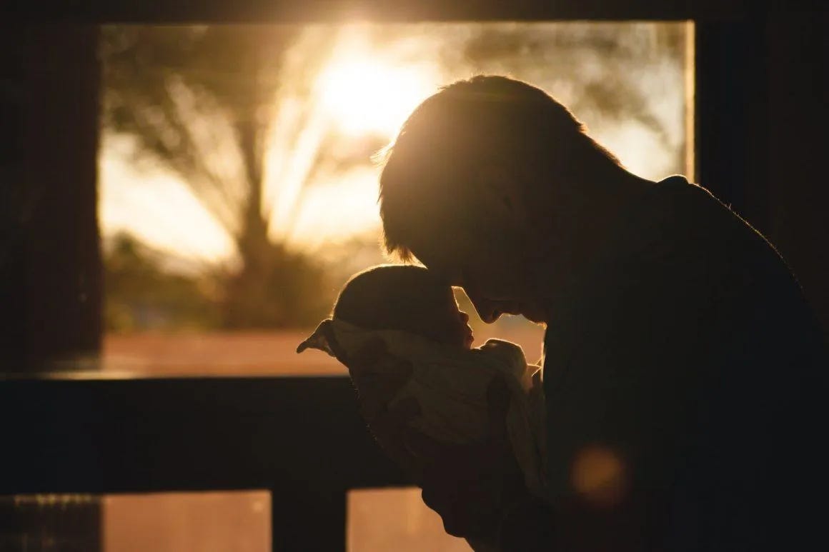 man carrying baby drawing their foreheads man carrying baby drawing their foreheads
