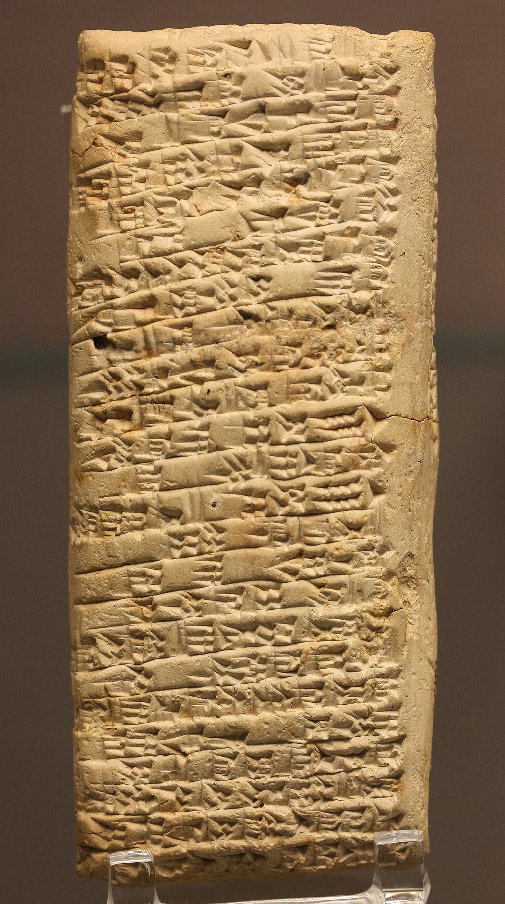 Ancient clay tablet with cuneiform script inscribed in rows.