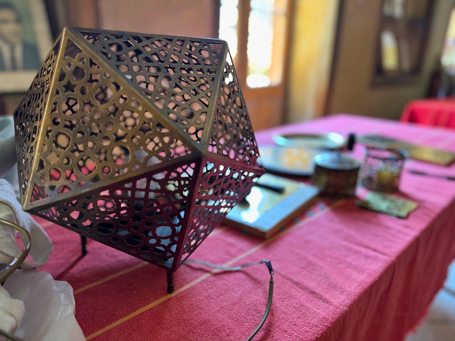 Geometric brass lamp with intricate cutwork by Noha El Qahwagy displayed on a table.