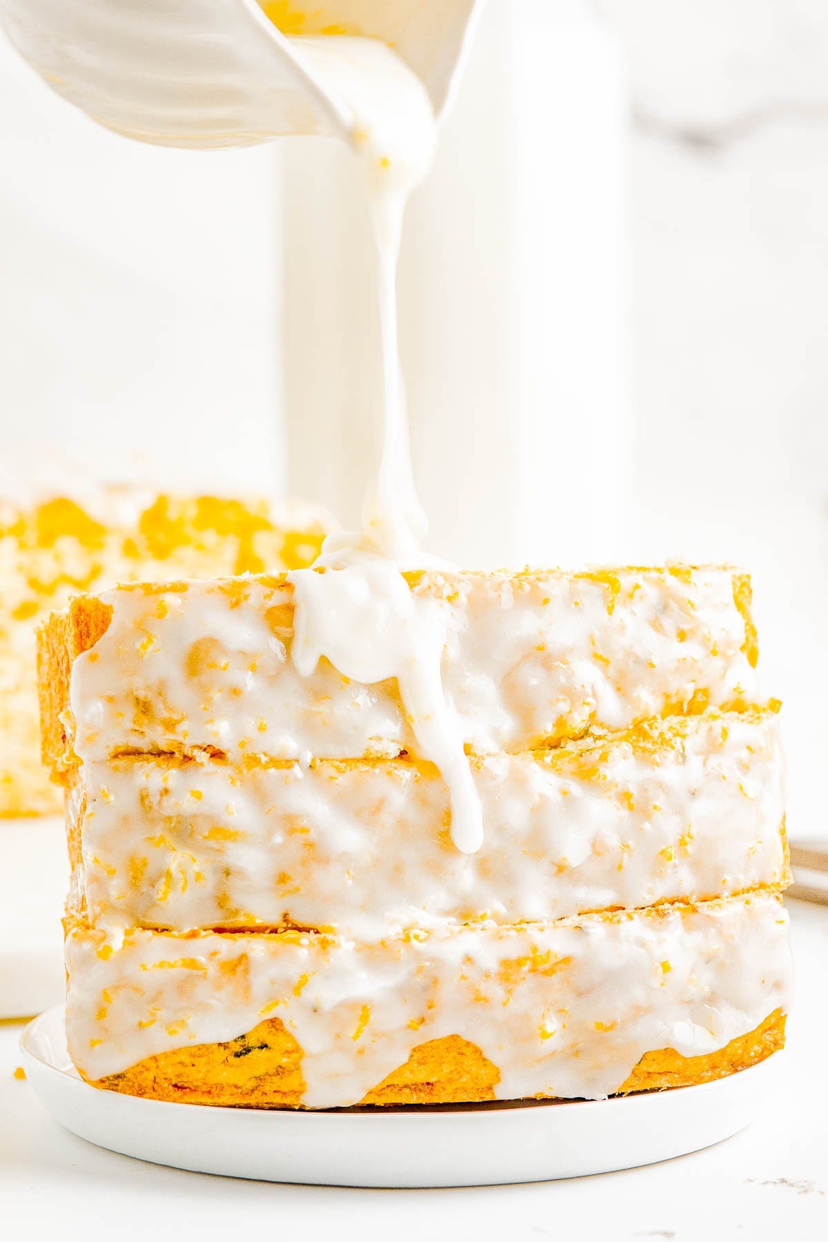 A stack of glazed lemon zucchini bread slices on a plate. A stack of glazed lemon zucchini bread slices on a plate.