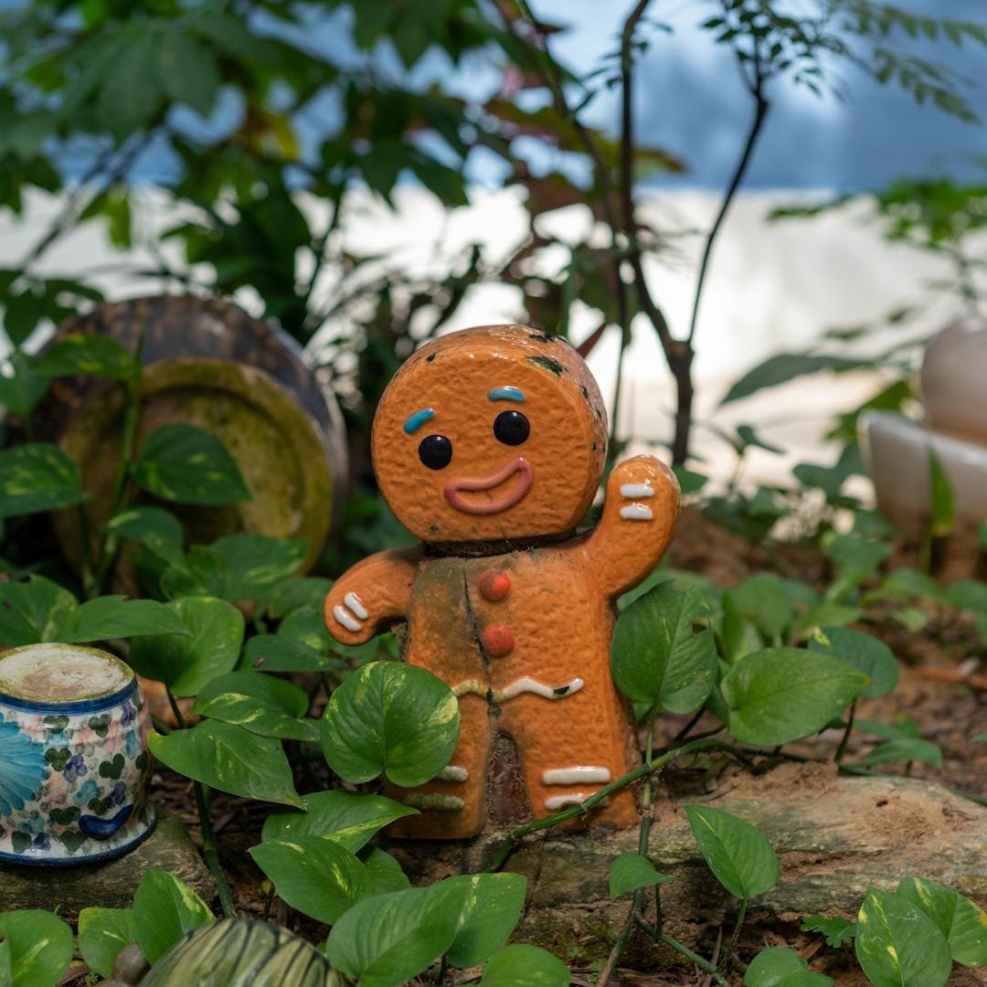 a gingerbread man figurine sitting in a garden a gingerbread man figurine sitting in a garden