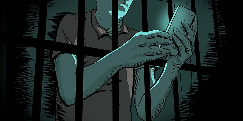 A graphic of a man behind bars with his arms through the bars, using a cell phone. A graphic of a man behind bars with his arms through the bars, using a cell phone.