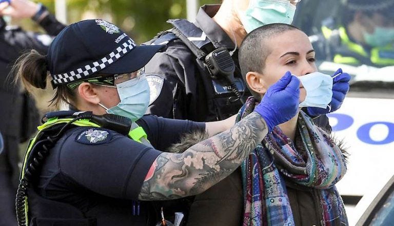An Australian lockdown protestor gets Covid-masked by a police officer. An Australian lockdown protestor gets Covid-masked by a police officer.