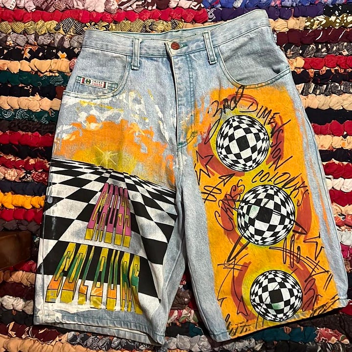 Images of brightly coloured shorts with graffiti, white t-shirt with the words Speak Yo Mind, multicolored cap with the words Cross Colours K-9 Club and image of a dog, and yellow, red, green, and blue patterned kente cloth shirt. 