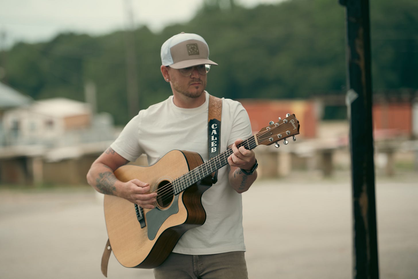  Caleb Wolfe stands beneath a covered market walkway, holding his black guitar case with confidence, dressed casually and ready to perform. Photos by Nakeshia Shannon of Shan Media Co @ShanMediaCo