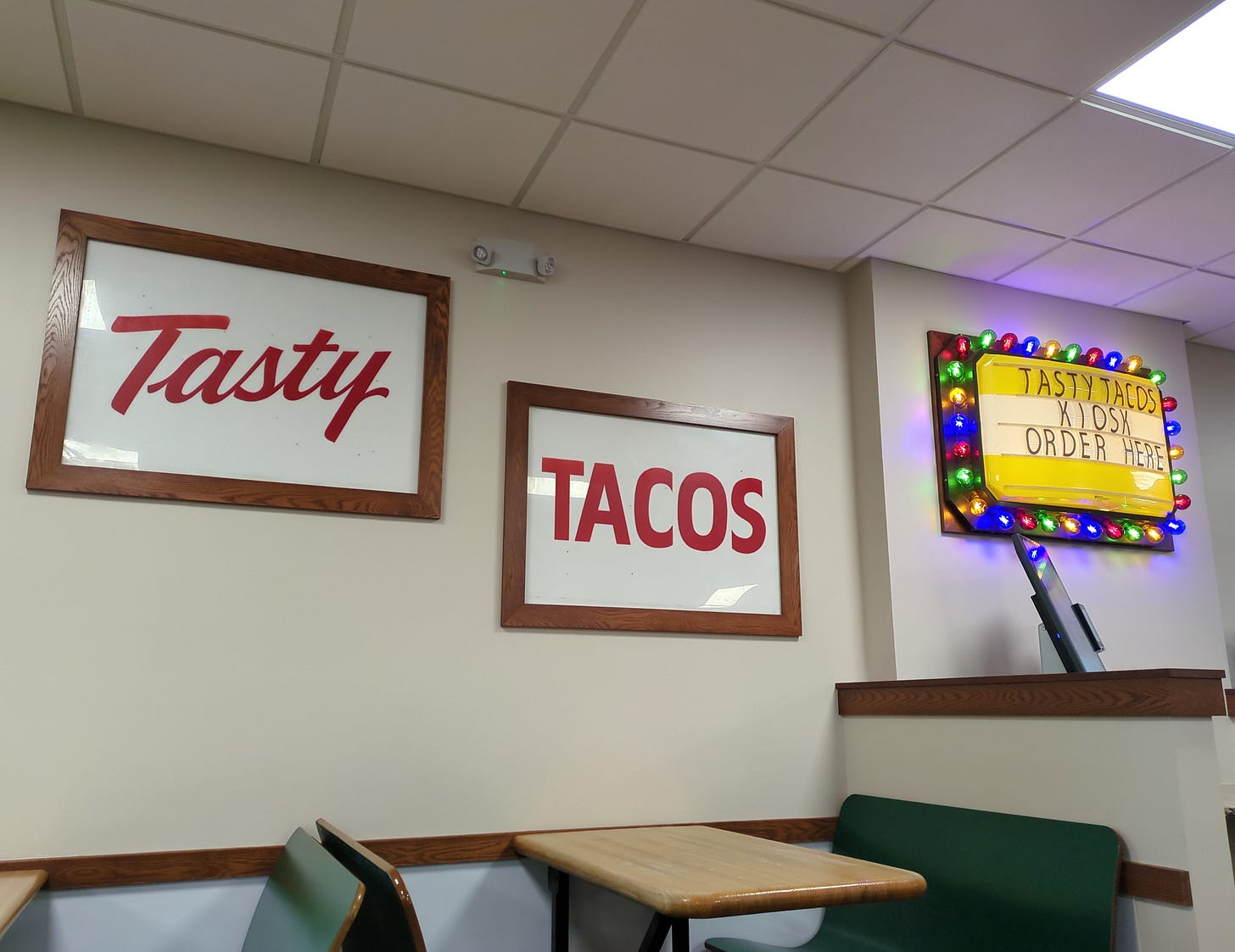Interior of Tasty Tacos with their name in frames and a colorful, lighted message board