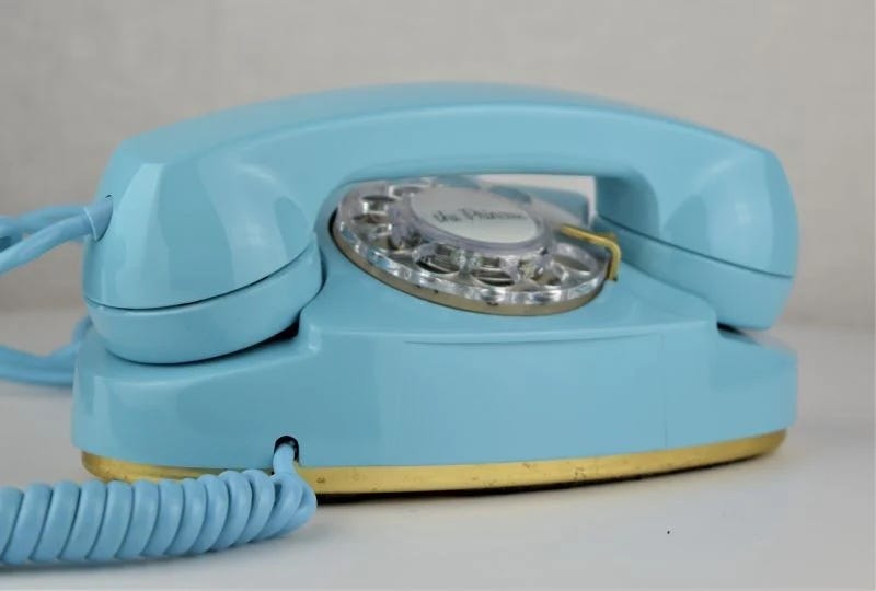 Vintage blue Princess rotary phone with a clear dial and gold base, featuring a coiled cord and classic design. Vintage blue Princess rotary phone with a clear dial and gold base, featuring a coiled cord and classic design.