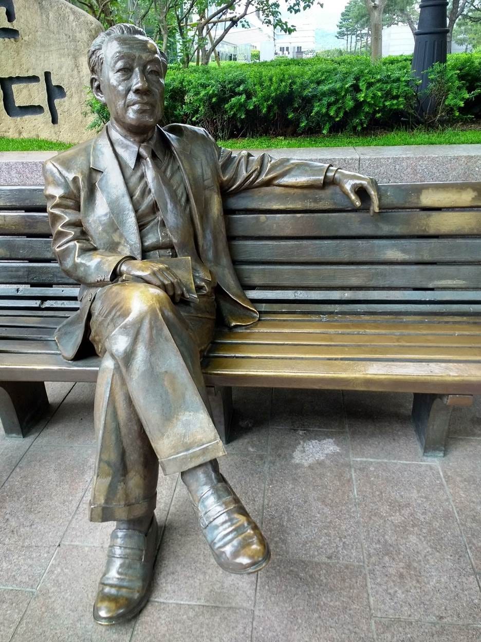A statue of a person sitting on a bench

AI-generated content may be incorrect.